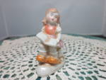 Girl Reading Book Made in Japan Figurine. She is adorable wearing her little jumper with orange top and brown skirt over a white blouse. She is has socks and orangish to brown color shoes. She appears...