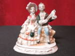 Occupied Japan figurine with a lovely couple seated while he plays his instrument. It has lovely color with nice gold trim and detail. It is  3 1/4 inches high, 3 inches wide and 1 3/4 inches deep. It...