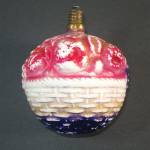 An extra large C-6 type figural milk glass Christmas tree lightbulb circa 1930s, in the shape of a basket of fruit. You can see apples, bananas, grapes, oranges, berries, and peaches in the basket, pl...