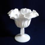 This pretty Fenton milk glass ruffled compote is in the Cactus pattern, produced from 1959 to 1962. It measures 5-3/4 inches high by 5-3/4 inches wide across the rim and is in perfect condition. <BR>