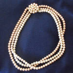 Each of the three strands of faux pearls in this Mid Century necklace is a different color: creamy off white, palest rosy beige, and a darker shade of pale beige-pink. The decorative clasp is a goldto...