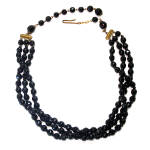 This vintage black glass triple strand beaded choker length necklace was made in Western Germany between 1947 and 1951. The softly faceted beads are all the same size (except for the two larger ones o...
