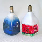 A pair of 1950s figural milk glass Christmas light bulbs in working condition. They're C-6 type, 2-1/2 inches high. The four-sided drop has embossed leaping reindeer on two sides, and Santa on his sle...