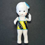 This 1930s Japan porcelain bisque doll is just over 4-1/2 inches tall. She wears a painted-on swimsuit and has a blue bow in her hair. The arms are strung, the legs and head are immobile. Incised Made...