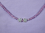 Amethyst & Celtic Hearts necklace. This strand of 4 mm Amethyst round beads is complemented by to silver plated Celtic hearts. 15mm sterling silver clasp. Approx. length:  19 1/2 inches.