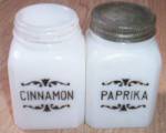 Old milk glass shaker with Cinnamon and one with paprika with scrolls enameled on the front. Cinnamon does not have a lid but otherwise excellent condition. Paprika has the original tin lid. Stands 3 ...