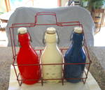 Three painted milk bottles with metal carrier. The bottles are copies of original 1800's Thatcher Dairy bottles. But these bottles and rack do look like fairly old copies, not like the newer copies pu...