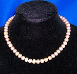 Classic Pink Pearl Necklace of 8.6mm Pink Genuine Freshwater Pearls. There is a large silver (NOT Sterling) clasp. The pearls are not round, more like a potato pearl...flat on one end. The necklace is...