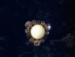 a lovley vintage purple rhinestone brooch/pin with a large white stone in the middle (I don't know what this is, but it feels like glass) the back of the pin is gilt looking, and the stones are very p...