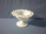 a footed/pedestal candy dish in milkglass with lace type edges. The dish is 5 inches across, and 3 1/4 inches tall, and has no chips.