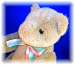 This lovely GUND TEDDY BEAR is soft and cuddley. He lives in a smoke free home and stands 15 inches tall.  His arms and legs are jointed. He sports a festive pink and light blue green ribbon around hi...