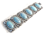 Large and very 50's signed KARU bracelet in silvertone with raised silver flowers, and vines with 6 large oval lucite/plastic faux turquoise set into it.The bracelet is 7 1/4 inches end to end, and 1 ...