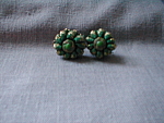 Wonderful screw back green ribbon earrings have a metal button in the middle with a green plastic button in the middle of the button. Earrings are 1" in diameter and has "Japan" on the ...