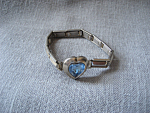 Wonderful heart shaped blue stone makes this child's bracelet look so shiny. Band is made of gilded brass interlocked linked plaques for easy fit. Has "Japan" on one of the links. In exce...