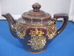 Cute little brown tea pot with flower designs.  Pot is 6" wide and has "Japan" on the bottom.  In excellent condition.