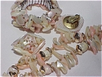 This is a vintage set consisting of a choker, clip earrings and flexible bracelet all set with mother of pearl shell pieces. The set has beautiful pink, peach and white coloring but I'm not sure how w...