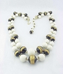 This is a vintage double strand necklace signed JAPAN.  The necklace is made of white glass beads and black glass beads with applied swirls of gold.  The necklace is adjustable and measures 16 to 18 i...