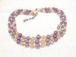 This is a vintage triple strand choker necklace signed JAPAN.  It has iridescent purple faux pearls, purple faux pearls, taupe art glass beads and iridescent faux pearls wrapped in gold tone wire.  Th...