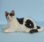 K0721b Lying Black & White Fat Cat, about 1.2" high, new porcelain miniature. 